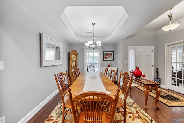 dining space with a notable chandelier, a tray ceiling, and hardwood / wood-style flooring