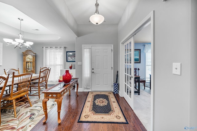 foyer featuring an inviting chandelier, dark hardwood / wood-style floors, a raised ceiling, and french doors