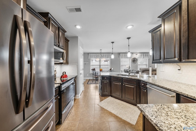 kitchen with pendant lighting, sink, light tile patterned floors, dark brown cabinetry, and stainless steel appliances