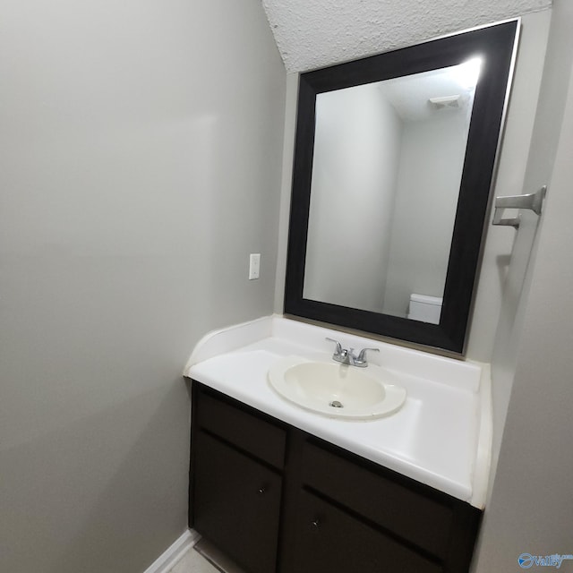 bathroom with vanity, a textured ceiling, and toilet