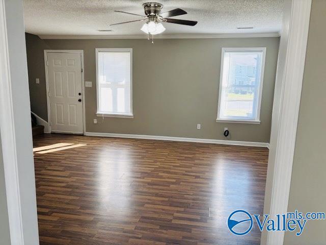 empty room featuring ceiling fan, dark hardwood / wood-style floors, crown molding, and a textured ceiling