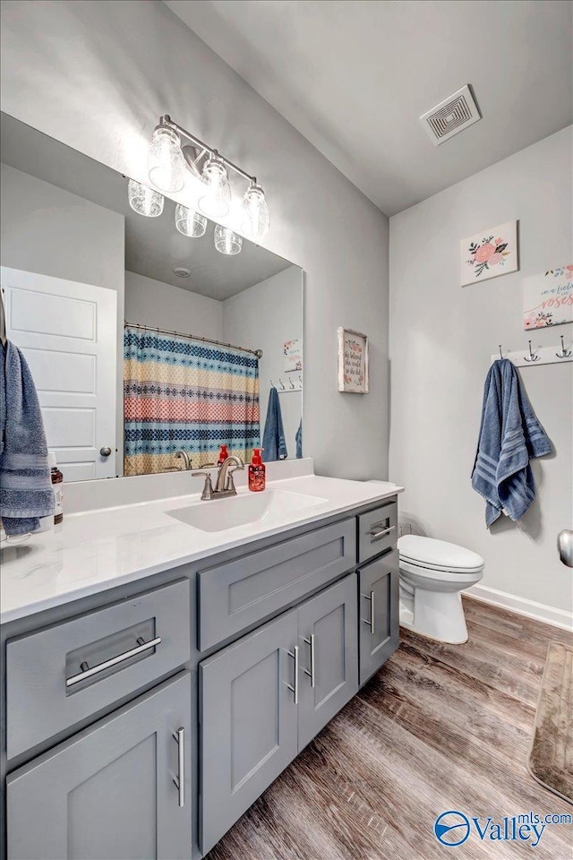 bathroom with toilet, vanity, and hardwood / wood-style floors