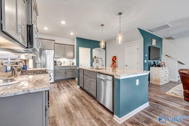 kitchen featuring decorative light fixtures, tasteful backsplash, sink, an island with sink, and stainless steel appliances