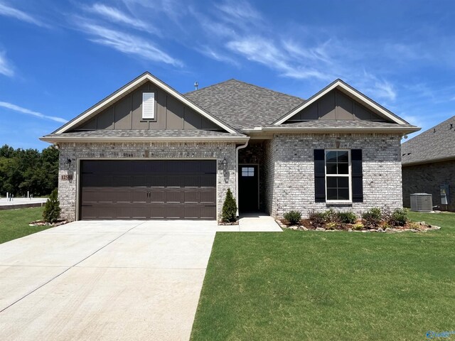 view of front of property featuring a garage, central AC, and a front lawn