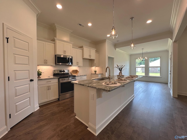 kitchen with white cabinetry, stainless steel appliances, ornamental molding, a kitchen island with sink, and dark wood-type flooring