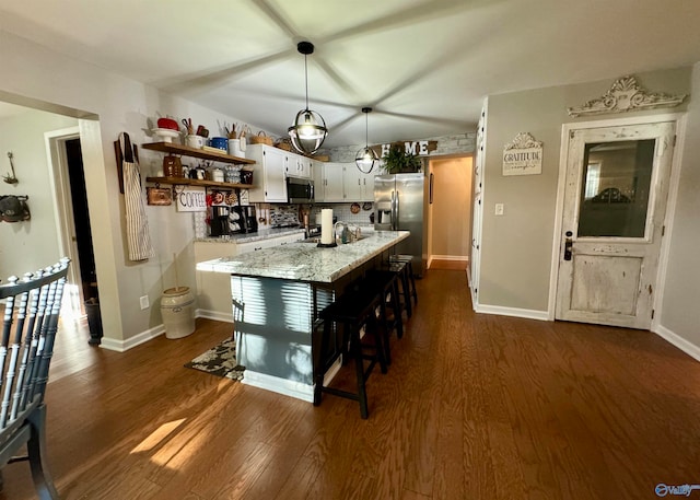 kitchen with pendant lighting, white cabinetry, appliances with stainless steel finishes, a center island, and a kitchen bar