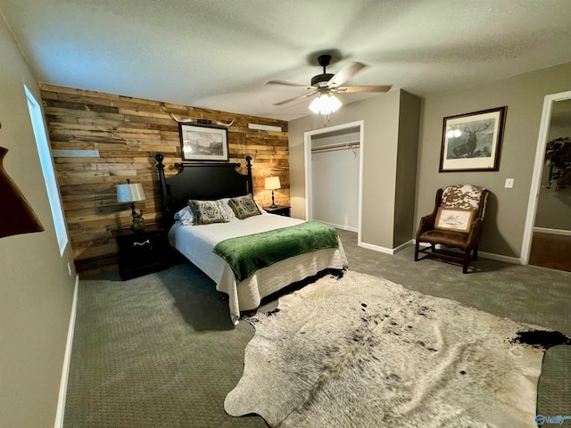 bedroom with a closet, a textured ceiling, wooden walls, carpet, and ceiling fan