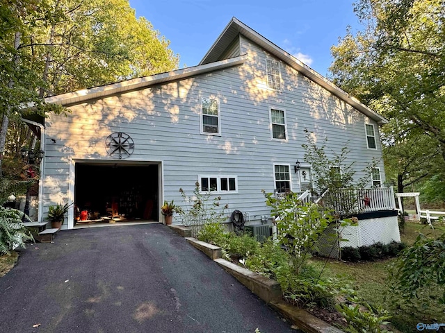 view of side of property with a garage, a deck, and central AC