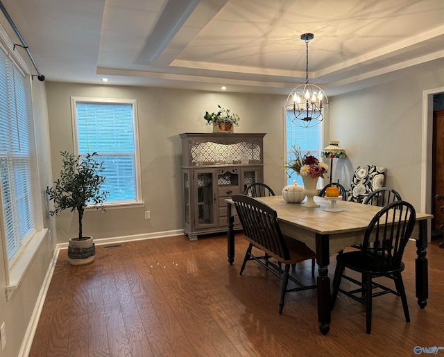 dining space featuring a raised ceiling, a chandelier, and dark hardwood / wood-style flooring