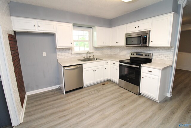 kitchen with sink, white cabinetry, appliances with stainless steel finishes, and light hardwood / wood-style floors