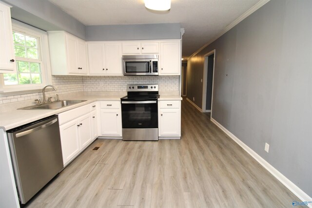 kitchen with white cabinetry, appliances with stainless steel finishes, sink, and light hardwood / wood-style flooring