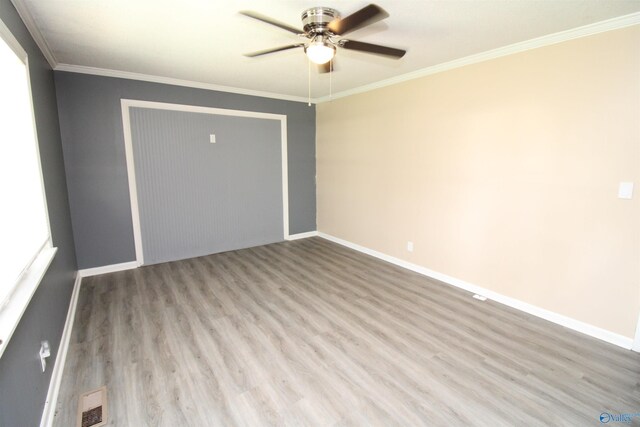 unfurnished bedroom with ceiling fan, a closet, crown molding, and wood-type flooring