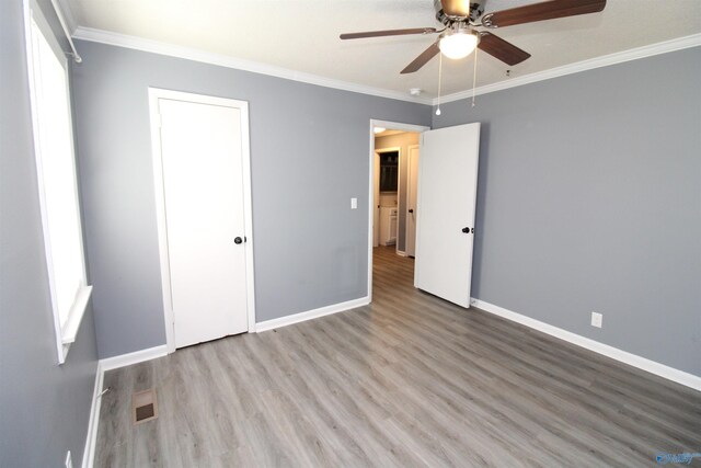 unfurnished bedroom featuring ceiling fan, wood-type flooring, and ornamental molding