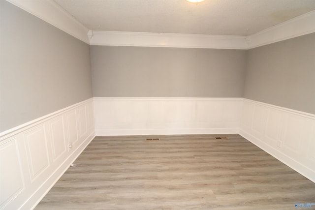 spare room with light wood-type flooring and crown molding