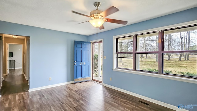 interior space with a healthy amount of sunlight, dark wood finished floors, visible vents, and baseboards