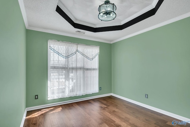 spare room featuring baseboards, wood finished floors, visible vents, and an inviting chandelier