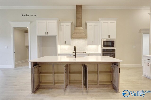 kitchen with built in microwave, a kitchen island with sink, stainless steel oven, and white cabinets