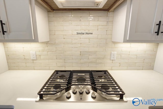 details with tasteful backsplash, stainless steel gas stovetop, and gray cabinetry