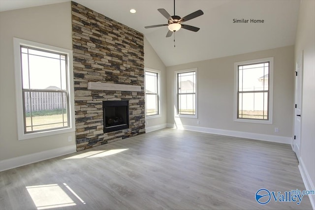 unfurnished living room featuring ceiling fan, a stone fireplace, high vaulted ceiling, and light hardwood / wood-style floors