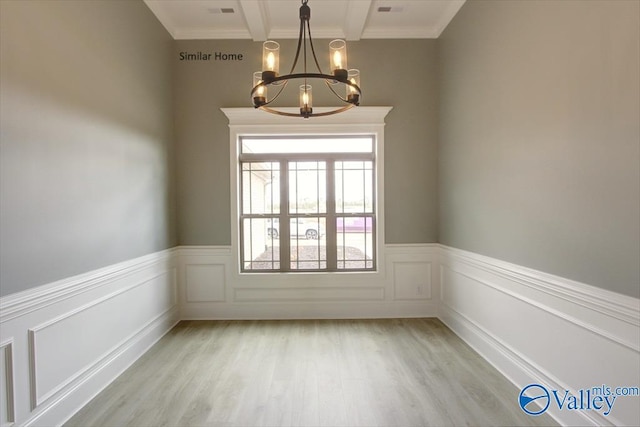 empty room with beam ceiling, a chandelier, and light hardwood / wood-style floors