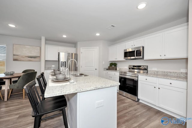 kitchen featuring white cabinetry, appliances with stainless steel finishes, sink, and a center island with sink