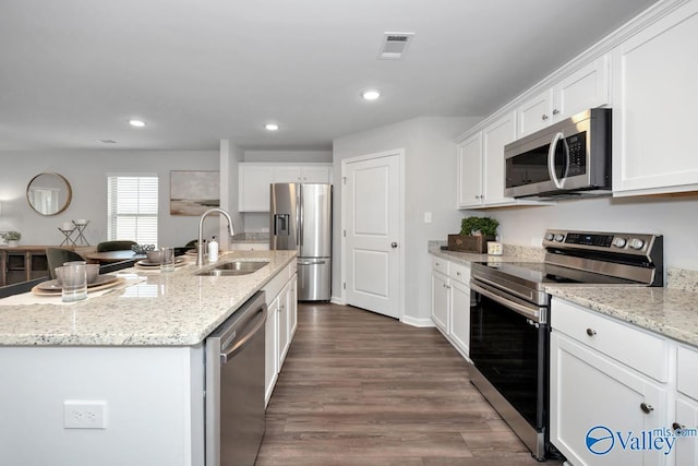 kitchen with sink, a center island with sink, appliances with stainless steel finishes, light stone countertops, and white cabinets