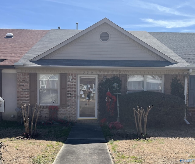 bungalow with brick siding and roof with shingles