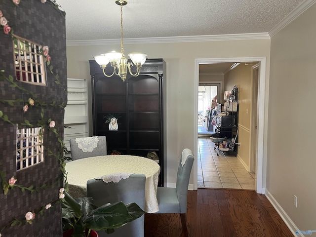 dining room featuring a chandelier, a textured ceiling, wood finished floors, baseboards, and crown molding