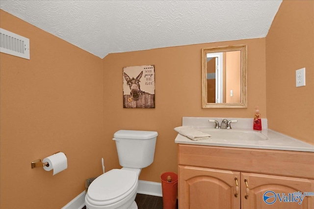 half bath with vanity, toilet, visible vents, baseboards, and a textured ceiling