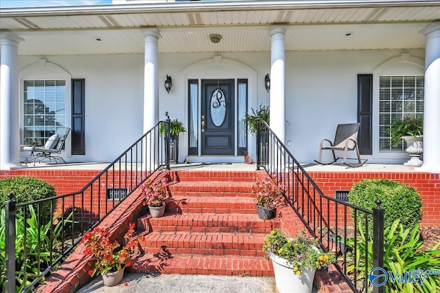 view of exterior entry featuring covered porch and stucco siding