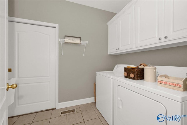 washroom featuring cabinet space, washing machine and clothes dryer, light tile patterned floors, visible vents, and baseboards