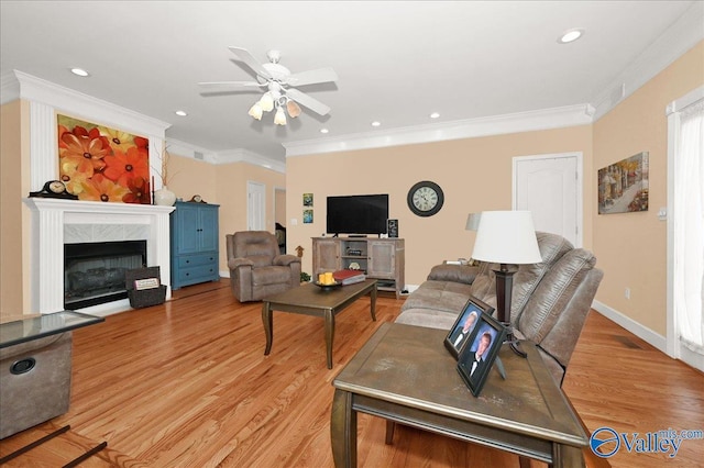 living room with ceiling fan, light wood-type flooring, ornamental molding, and a premium fireplace