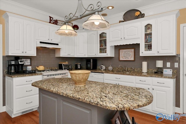 kitchen featuring a sink, white cabinets, under cabinet range hood, and white appliances