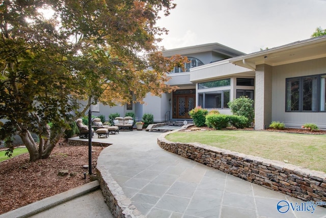 exterior space with a patio, a balcony, and a front lawn