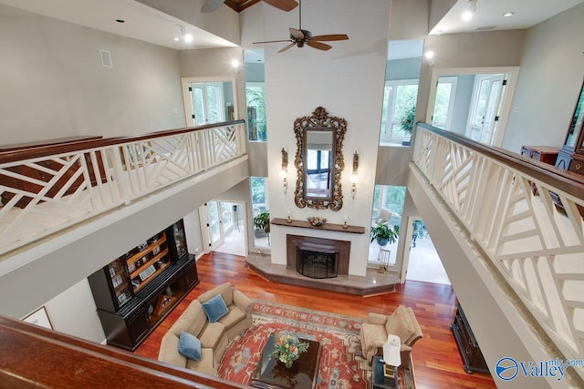 living room featuring ceiling fan, hardwood / wood-style floors, and a towering ceiling