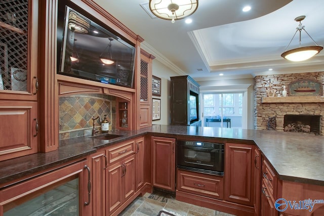 interior space featuring pendant lighting, crown molding, sink, a stone fireplace, and black oven