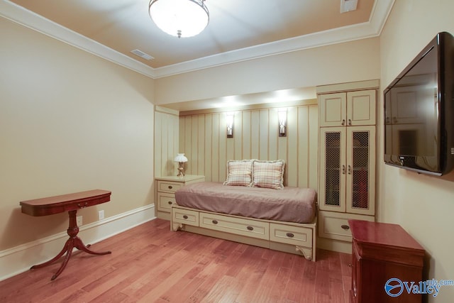 bedroom with crown molding and light hardwood / wood-style floors