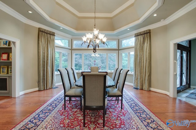 dining room with a notable chandelier, hardwood / wood-style floors, crown molding, and a raised ceiling