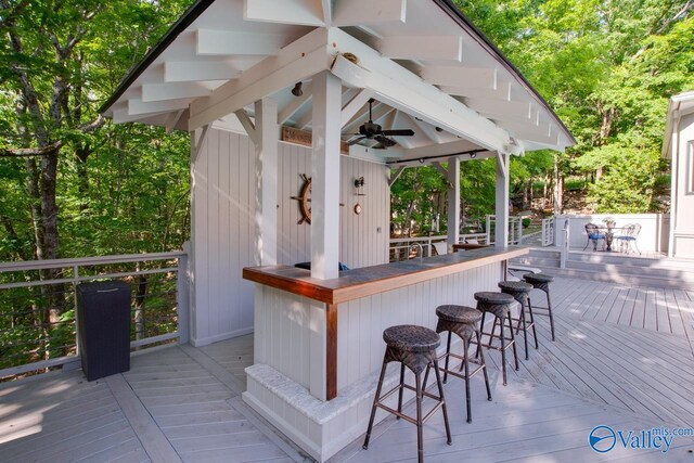 wooden terrace featuring ceiling fan and exterior bar