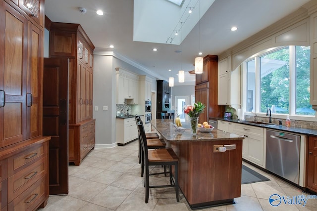 kitchen featuring dark stone counters, decorative light fixtures, sink, dishwasher, and a kitchen island