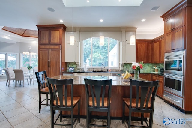 kitchen with decorative backsplash, stainless steel double oven, and hanging light fixtures