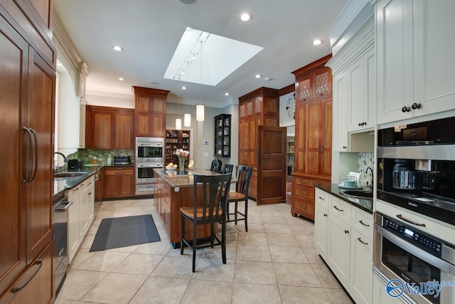 kitchen with decorative light fixtures, a skylight, sink, a kitchen island, and a breakfast bar