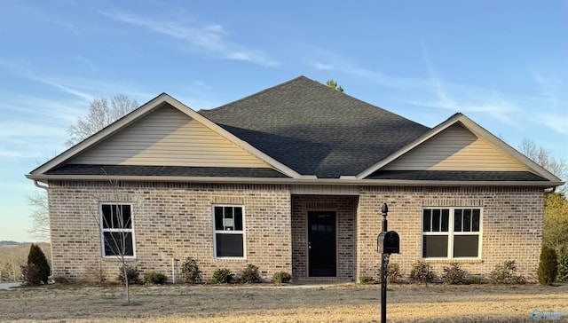 view of front of property featuring brick siding and roof with shingles