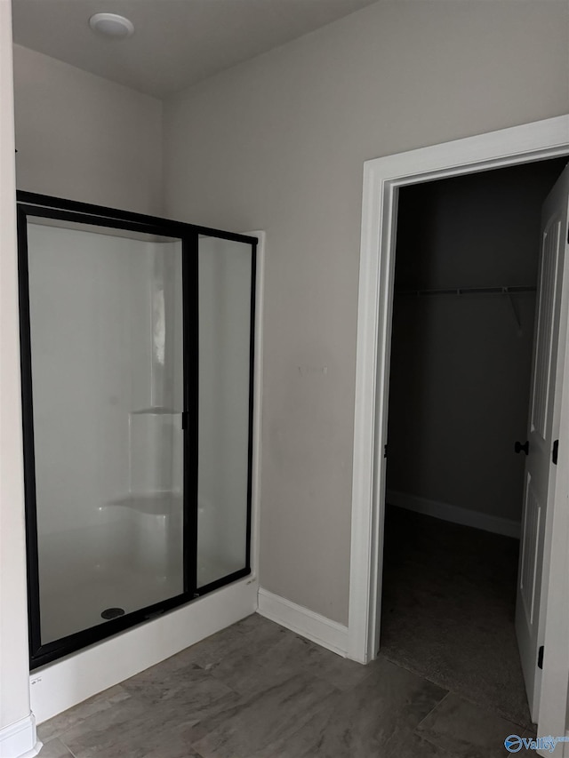 bathroom featuring a stall shower, a walk in closet, and baseboards