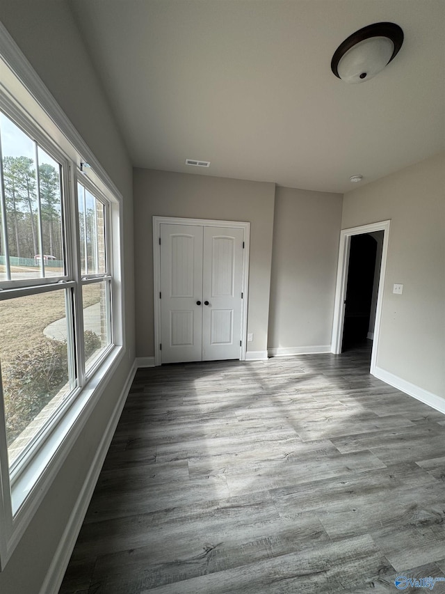 empty room featuring visible vents, baseboards, and wood finished floors