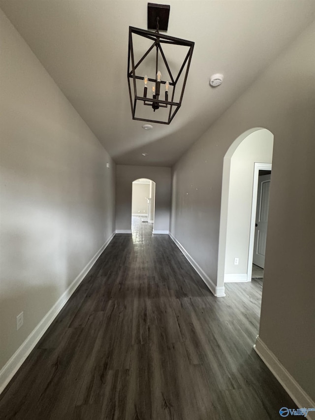 interior space with baseboards, arched walkways, and dark wood-type flooring