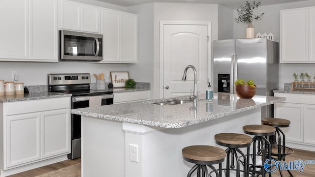 403 Jackson Point Cir, Huntsville, AL 35811 - kitchen featuring appliances with stainless steel finishes, wood finished floors, white cabinetry, and a breakfast bar area
