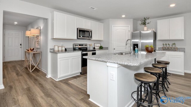 403 Jackson Point Cir, Huntsville, AL 35811 - kitchen with stainless steel appliances, light wood-type flooring, recessed lighting, a kitchen bar, and white cabinets