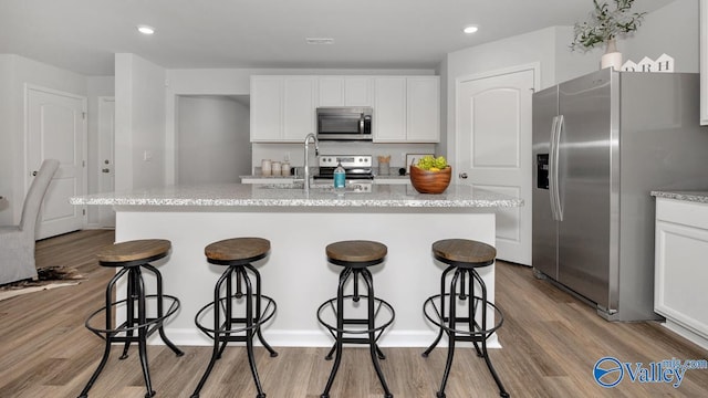 403 Jackson Point Cir, Huntsville, AL 35811 - kitchen featuring appliances with stainless steel finishes, a kitchen bar, light wood-style floors, white cabinets, and recessed lighting