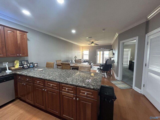 kitchen with crown molding, a peninsula, stainless steel dishwasher, and light wood finished floors